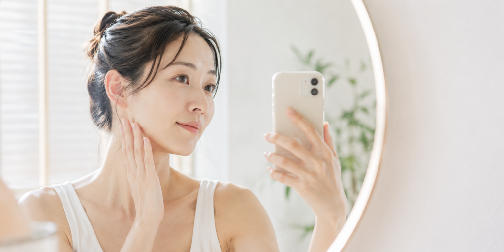 フェイスラインが気になり鏡で確認している30代女性。エラ張りと食いしばりの関係を解説する記事のイメージ